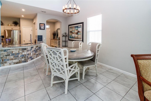 dining space with recessed lighting, arched walkways, an inviting chandelier, light tile patterned floors, and baseboards