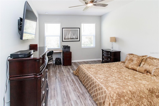 bedroom with a ceiling fan, multiple windows, wood finished floors, and baseboards