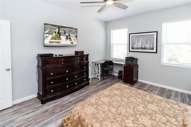 home office featuring plenty of natural light, a ceiling fan, baseboards, and wood finished floors