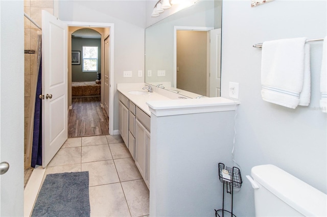 ensuite bathroom featuring tile patterned flooring, toilet, vanity, ensuite bath, and a shower