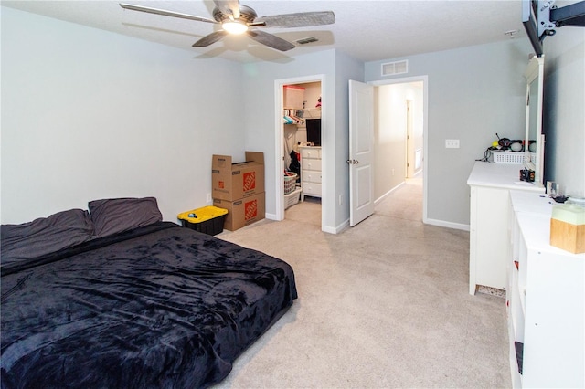 bedroom featuring baseboards, visible vents, ceiling fan, a spacious closet, and light carpet