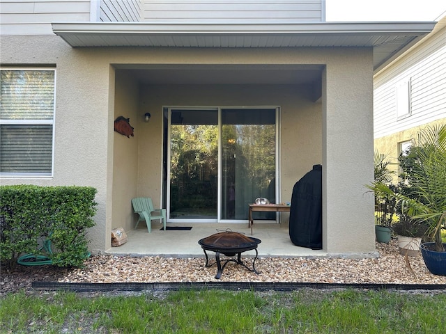 view of exterior entry with stucco siding and a patio