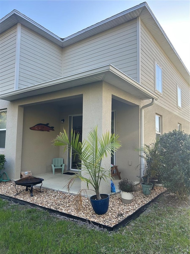 view of side of home with a patio, an outdoor fire pit, and stucco siding