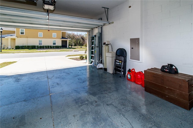 garage with electric panel, a garage door opener, and concrete block wall