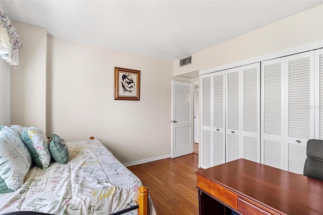 bedroom featuring dark wood-style floors, visible vents, a closet, and baseboards