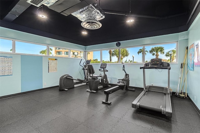 exercise room featuring visible vents, a healthy amount of sunlight, and baseboards