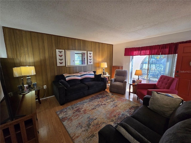 living room featuring wood finished floors, wood walls, and a textured ceiling