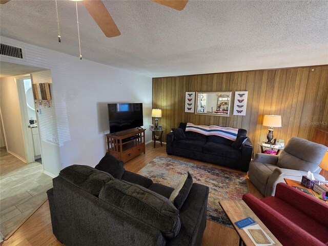 living room with visible vents, a textured ceiling, a ceiling fan, and light wood finished floors