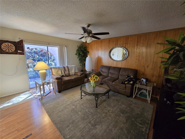 living area featuring a textured ceiling, wood finished floors, and wooden walls