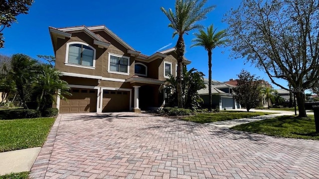 view of front of home featuring stucco siding, decorative driveway, and an attached garage