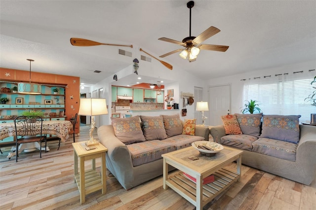 living room with a ceiling fan, lofted ceiling, visible vents, and light wood-style flooring