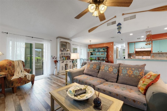 living area with lofted ceiling, light wood-type flooring, visible vents, and ceiling fan