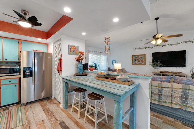 kitchen with light wood-style flooring, recessed lighting, a peninsula, open floor plan, and appliances with stainless steel finishes