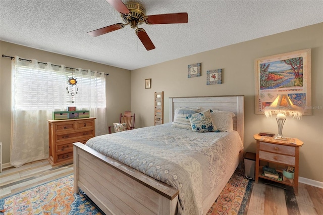 bedroom featuring light wood-type flooring, ceiling fan, a textured ceiling, and baseboards