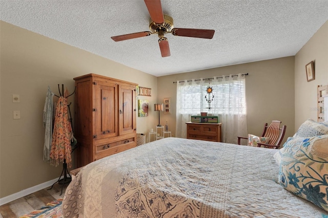 bedroom with a textured ceiling, ceiling fan, wood finished floors, and baseboards