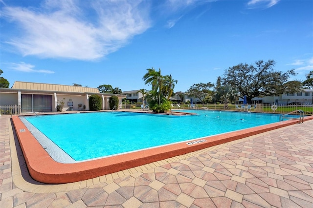 community pool with a patio and fence