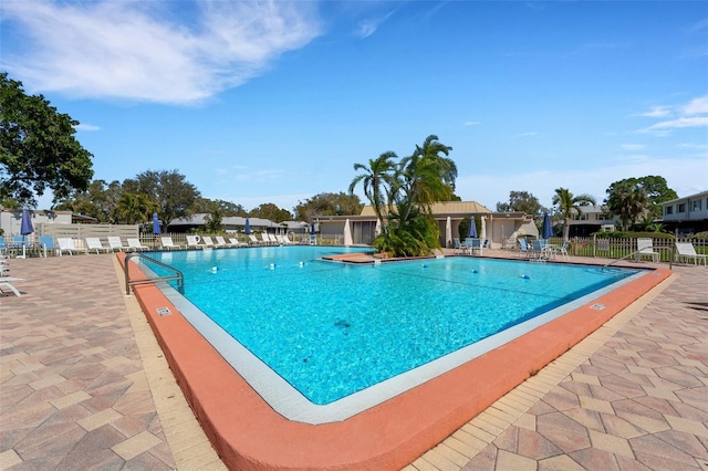 community pool with a patio and fence