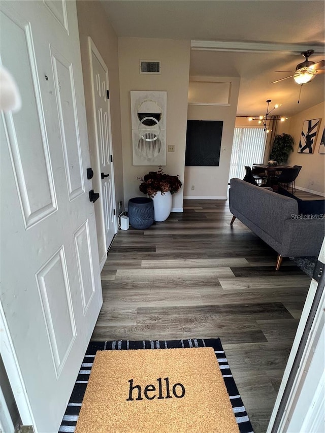 hall featuring dark wood-type flooring, visible vents, and baseboards