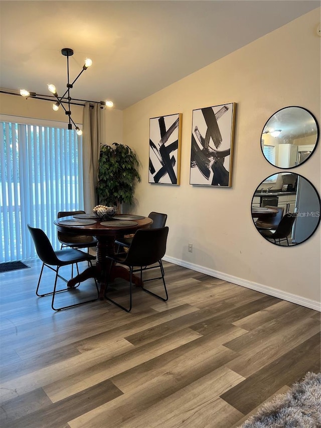 dining room with lofted ceiling, a notable chandelier, baseboards, and dark wood-style flooring