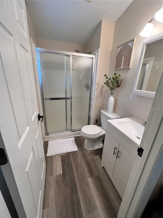 bathroom featuring toilet, a shower stall, vanity, and wood finished floors