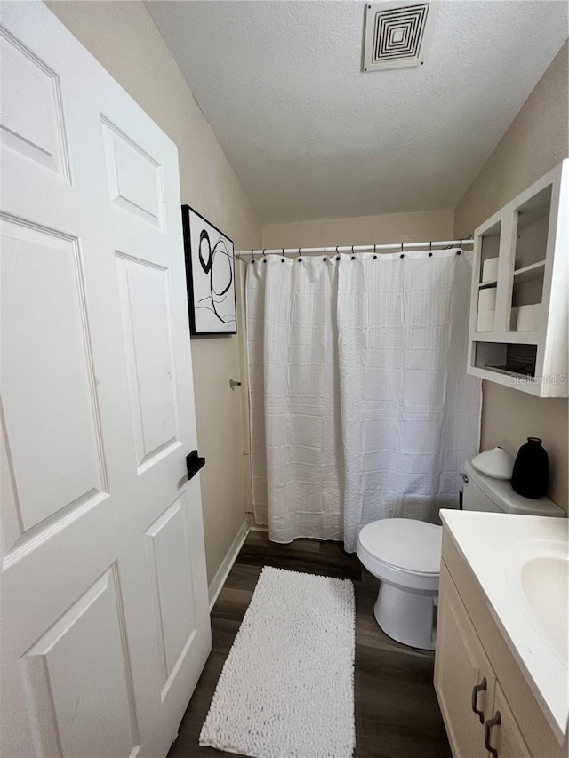 bathroom with visible vents, toilet, wood finished floors, a textured ceiling, and vanity