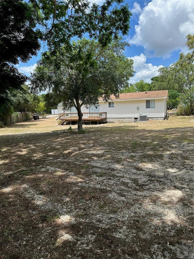 view of yard with central air condition unit and a wooden deck