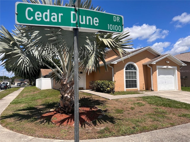 view of front facade with concrete driveway, a front yard, an attached garage, and stucco siding