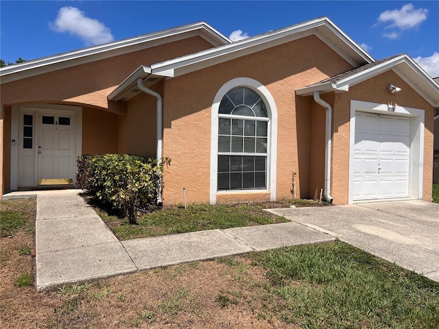 view of front of house featuring an attached garage, concrete driveway, and stucco siding