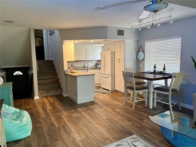 kitchen featuring a peninsula, wood finished floors, visible vents, backsplash, and freestanding refrigerator