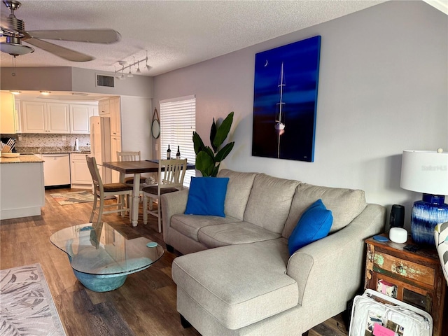 living area with a textured ceiling, ceiling fan, visible vents, light wood-style floors, and track lighting