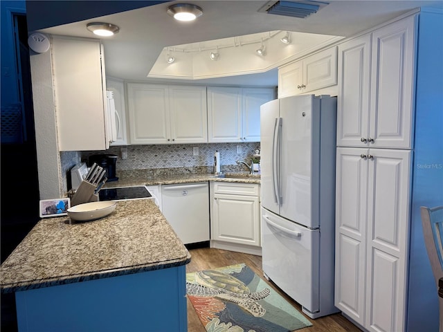 kitchen with white cabinets, white appliances, visible vents, and wood finished floors