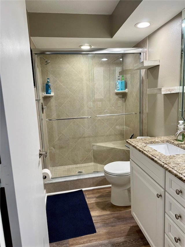 bathroom featuring vanity, wood finished floors, toilet, and a shower stall