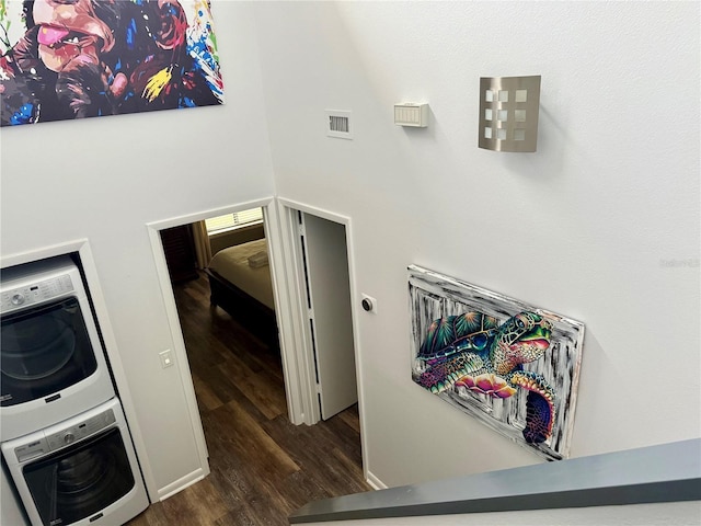 interior space featuring dark wood-type flooring, stacked washer / dryer, and visible vents