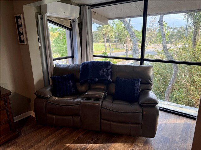 cinema room featuring a wall unit AC and wood finished floors