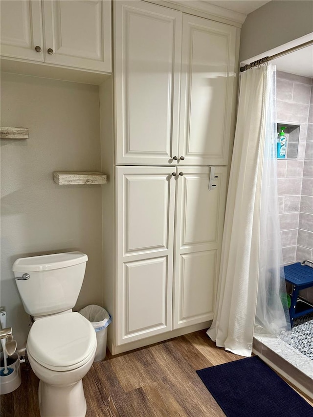 full bathroom with toilet, wood finished floors, and tiled shower