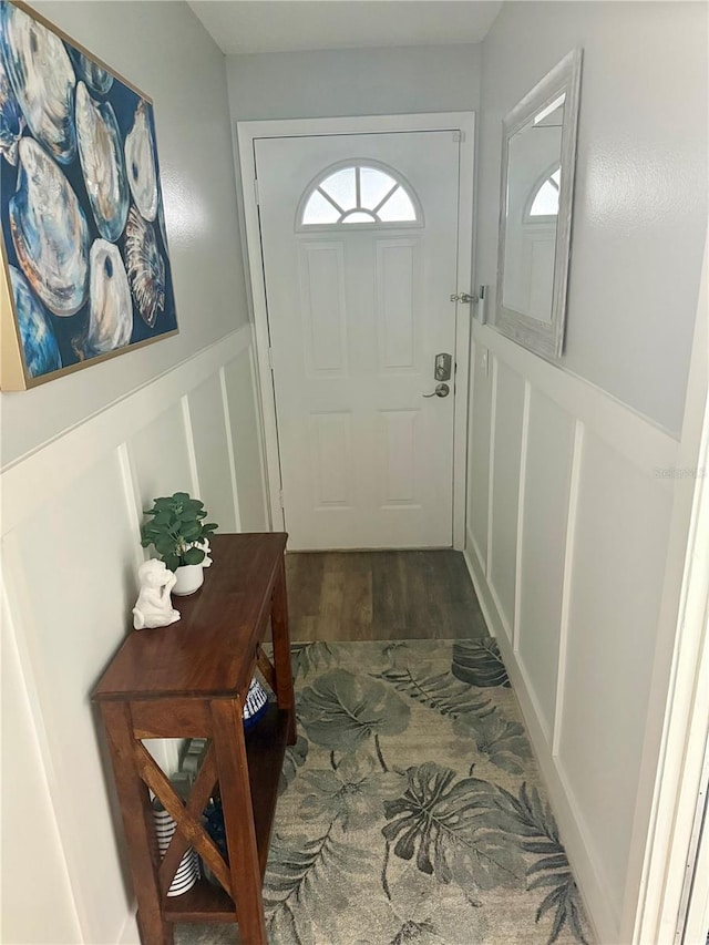 entryway with wainscoting, a decorative wall, and wood finished floors