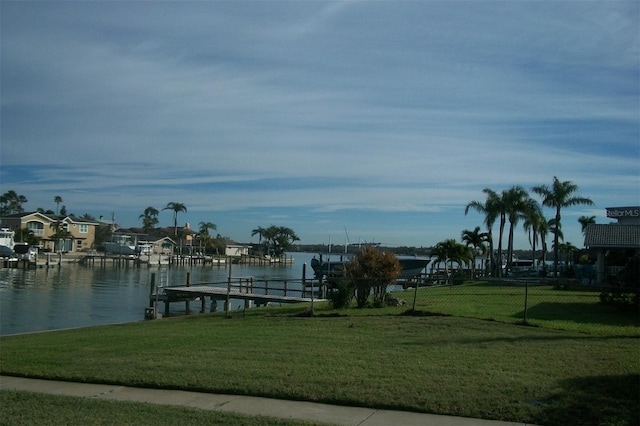 surrounding community featuring boat lift, a water view, a lawn, a boat dock, and fence