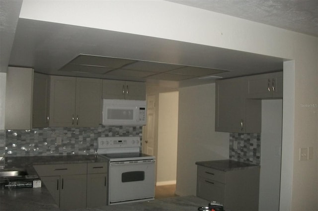 kitchen with a sink, white appliances, dark countertops, and backsplash