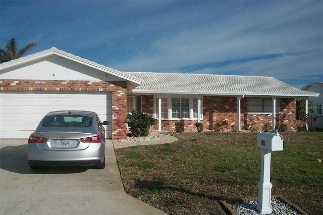 single story home with a front yard, concrete driveway, brick siding, and an attached garage