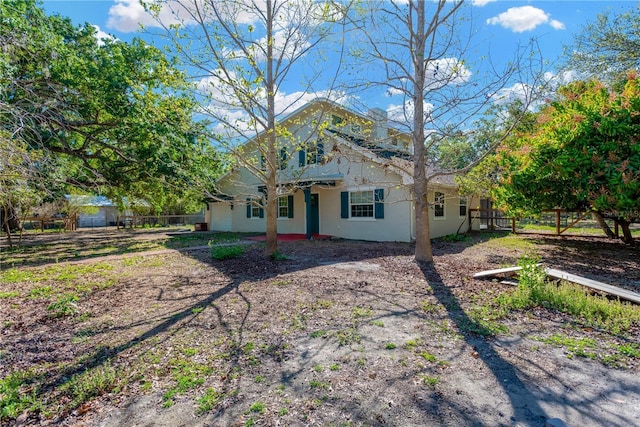 rear view of property with stucco siding and fence