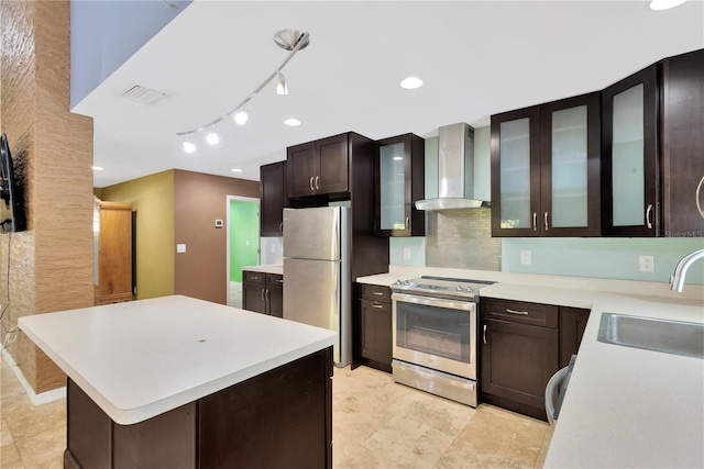 kitchen with visible vents, wall chimney range hood, light countertops, stainless steel appliances, and a sink