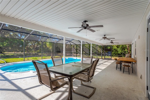 view of patio / terrace featuring a lanai, outdoor dining space, an outdoor pool, and a ceiling fan