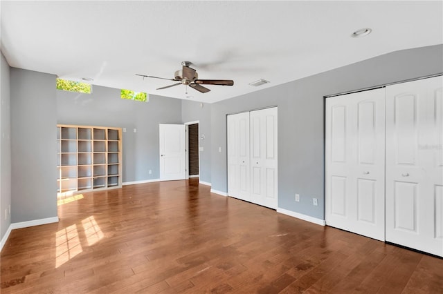 unfurnished bedroom featuring visible vents, baseboards, two closets, and wood finished floors