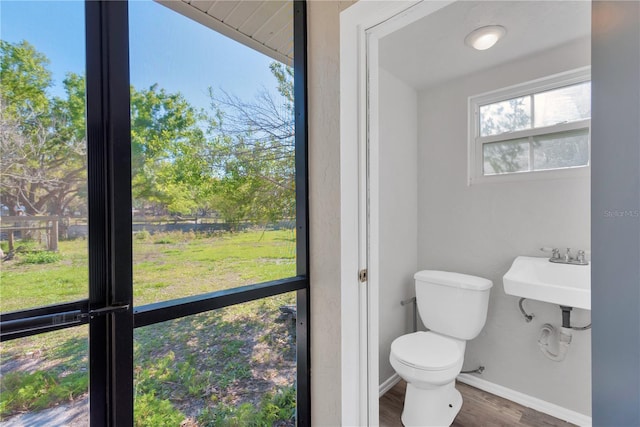 half bath featuring toilet, wood finished floors, and baseboards