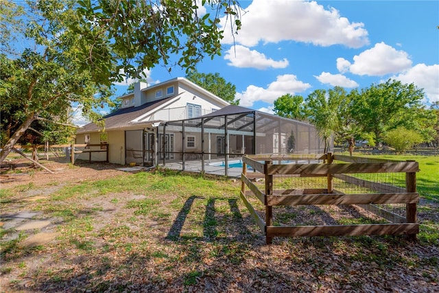 view of yard with glass enclosure, fence, and a fenced in pool