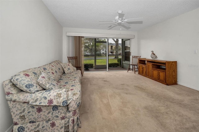 living area featuring a textured ceiling, ceiling fan, carpet, and baseboards