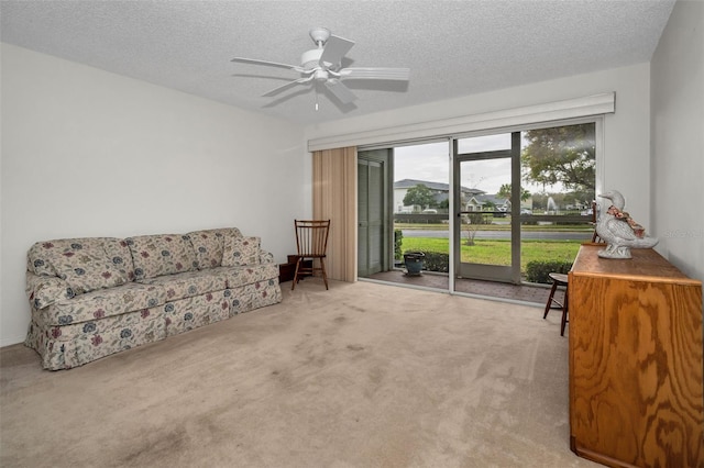 living area featuring carpet, ceiling fan, and a textured ceiling