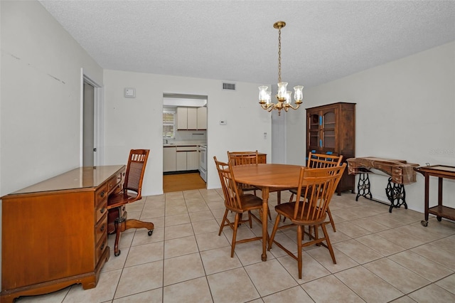 dining area featuring visible vents, a notable chandelier, a textured ceiling, and light tile patterned flooring