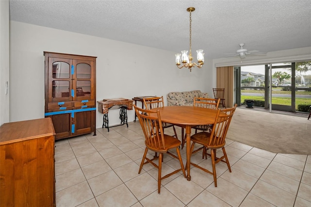 dining space featuring a textured ceiling, ceiling fan with notable chandelier, light tile patterned flooring, and light colored carpet