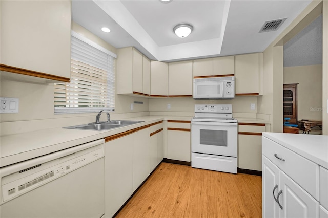 kitchen with white appliances, visible vents, light wood-style flooring, light countertops, and a sink